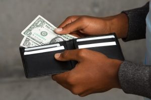 close up of man’s hands pulling dollar bills out of a wallet