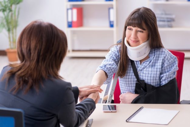 woman with neck brace speaking to lawyer