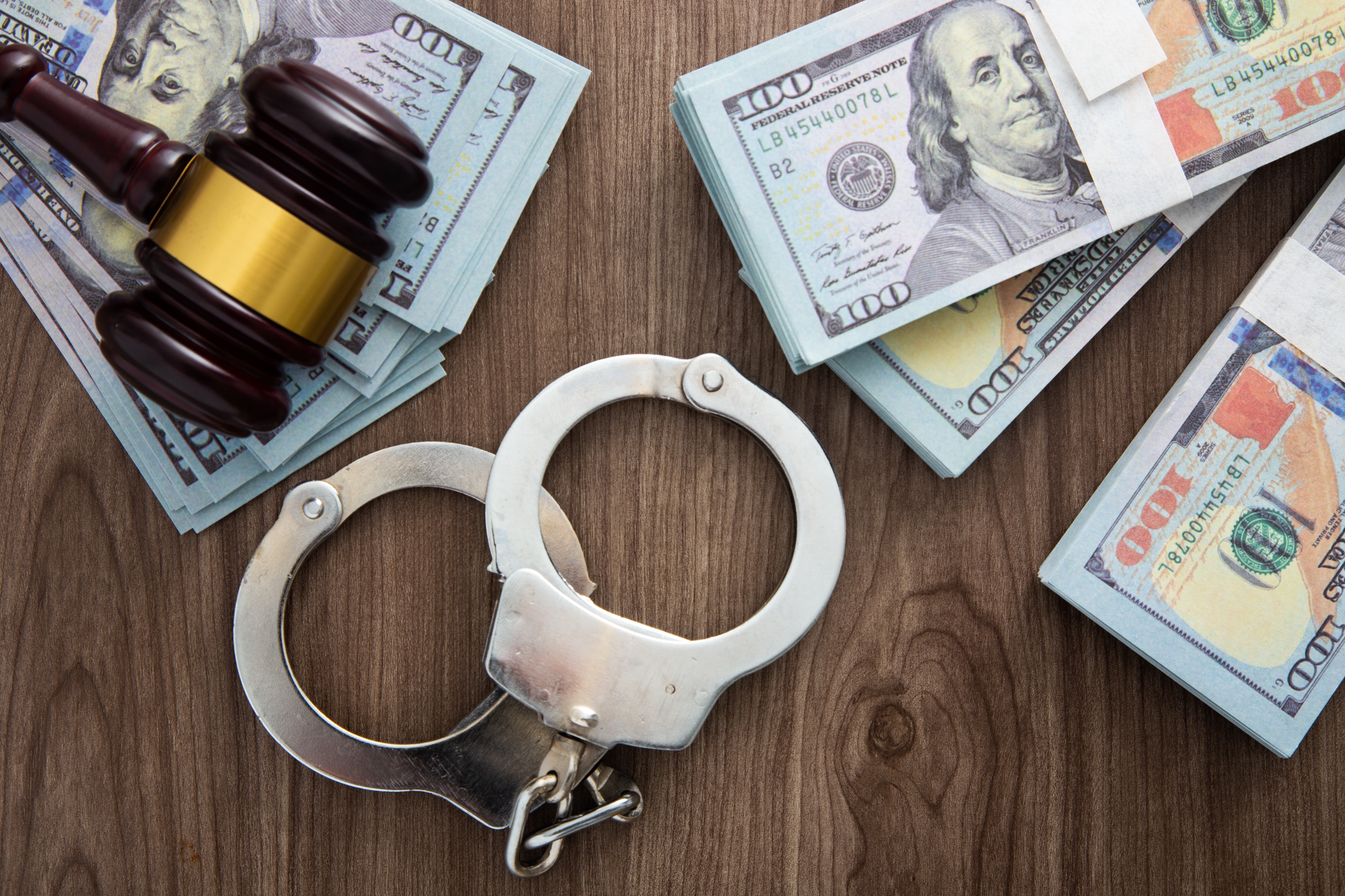 Gavel handcuffs and hundred dollar bills representing assault and battery defense Tampa cases